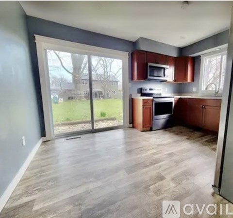 A kitchen with a wooden floor and a window overlooking a yard.