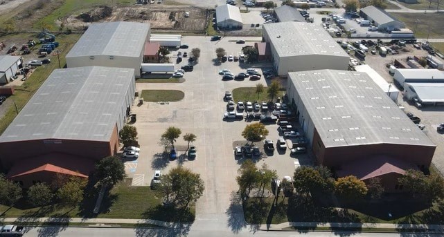 An aerial view of a parking lot with several cars and buildings.