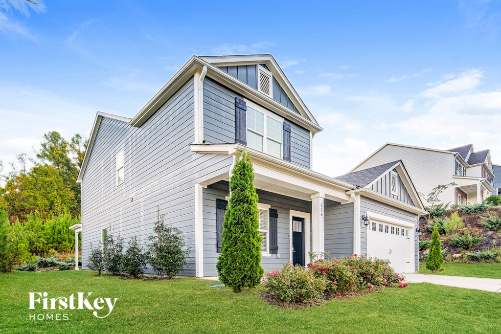A house with a grey exterior and a white garage door is for sale.
