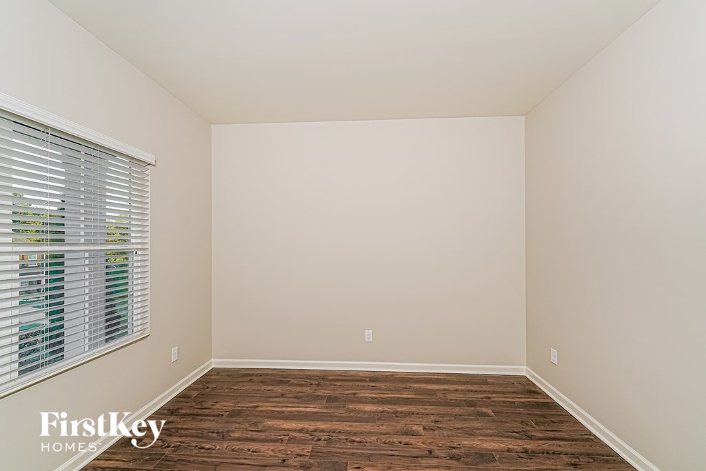 A room with wooden flooring and a window with blinds.