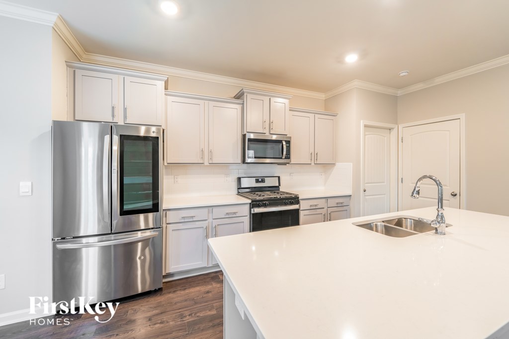 A kitchen with a stainless steel refrigerator, microwave, and oven.