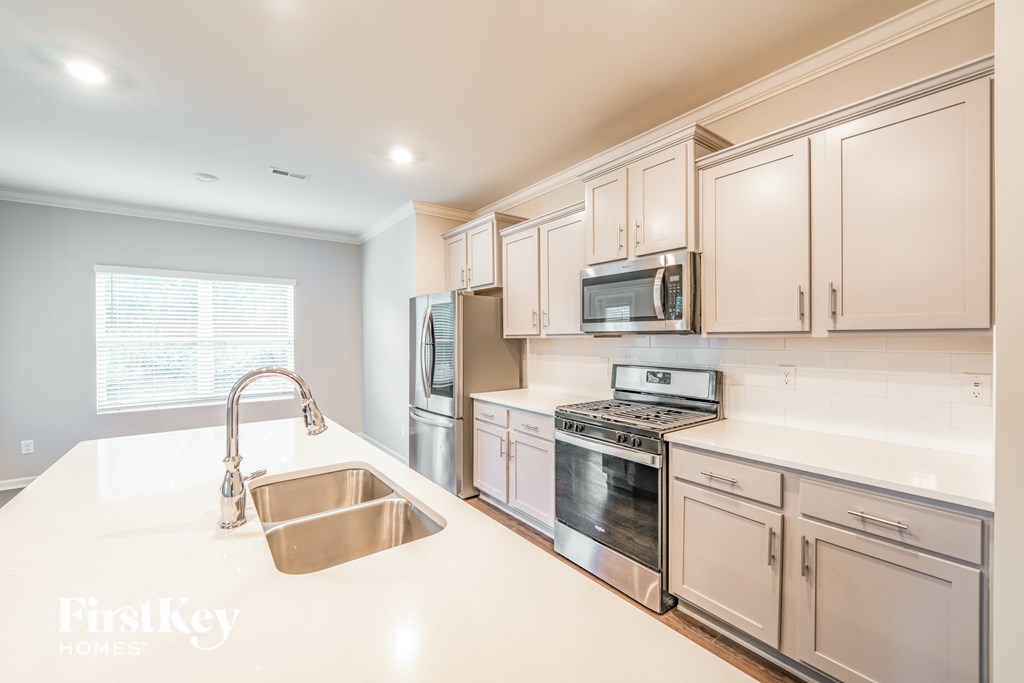 A kitchen with a sink, stove, and microwave.