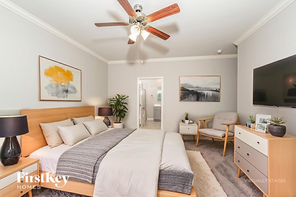 A bedroom with a bed, a chair, a dresser, and a ceiling fan.