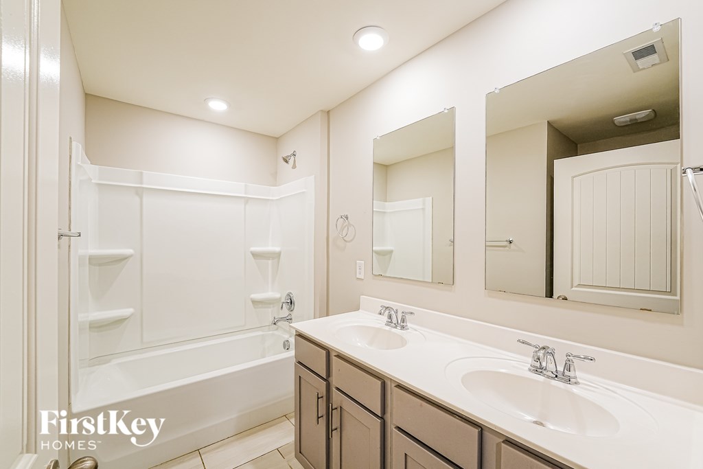 A white bathroom with a tub, sink, and mirror.