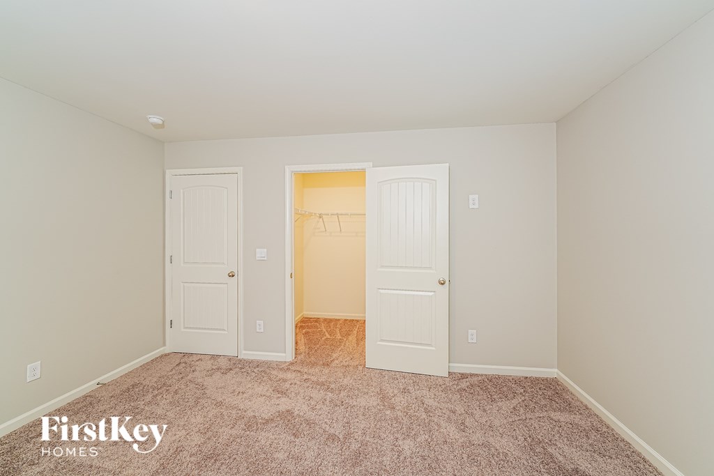 A room with a carpeted floor and two doors, one of which is open.