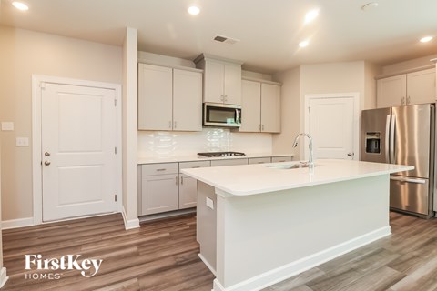 A kitchen with white cabinets and a white island.