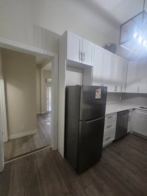 A black refrigerator in a kitchen with white cabinets.