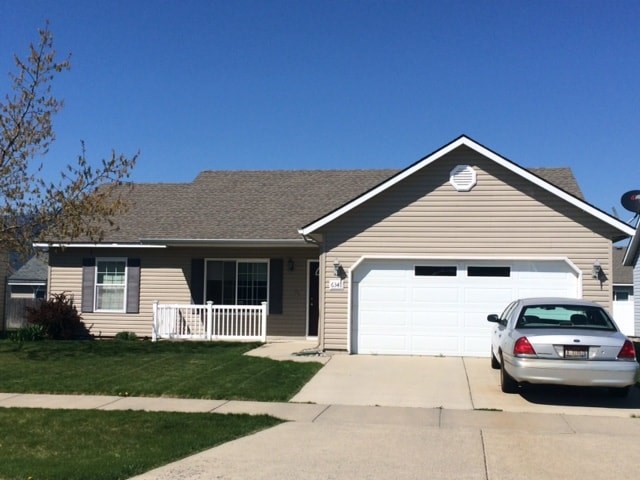 A silver car is parked in front of a garage.
