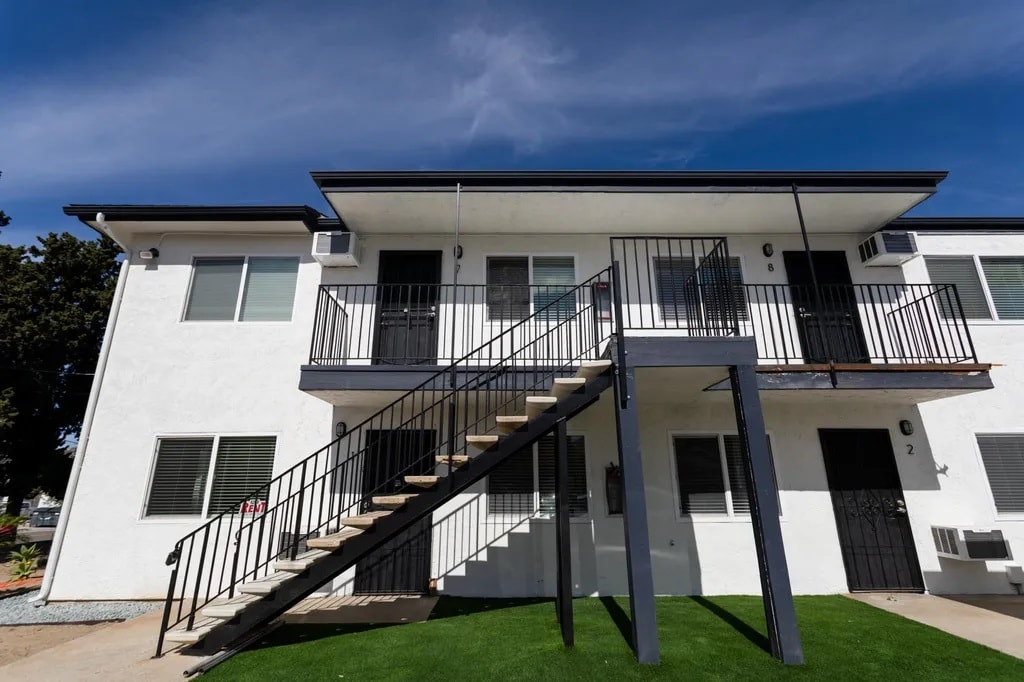 A white two-story house with a black metal staircase.