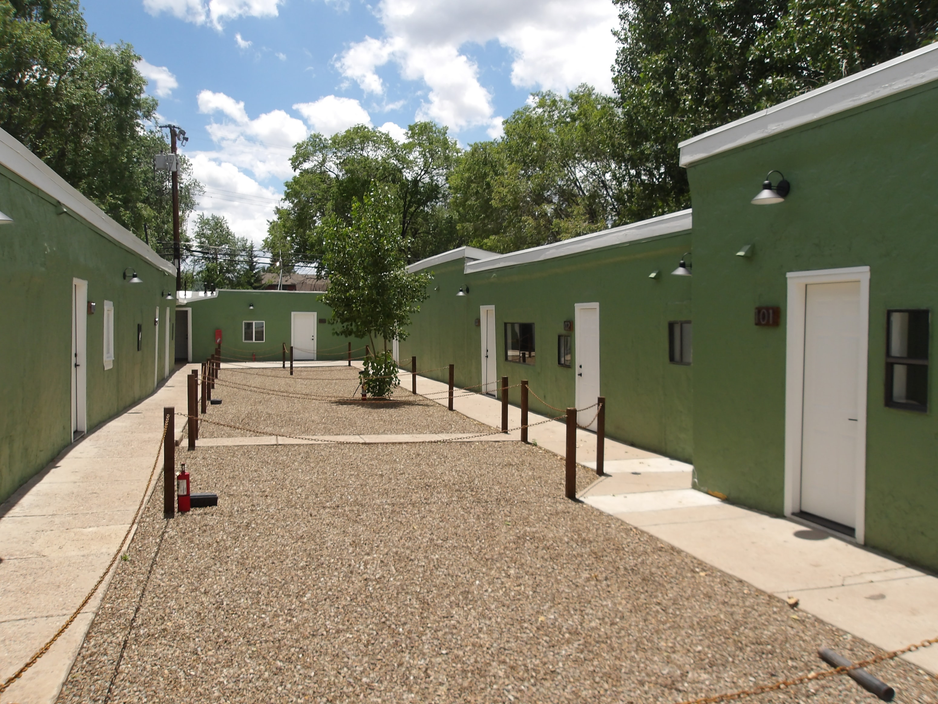 A courtyard surrounded by green buildings with white doors.
