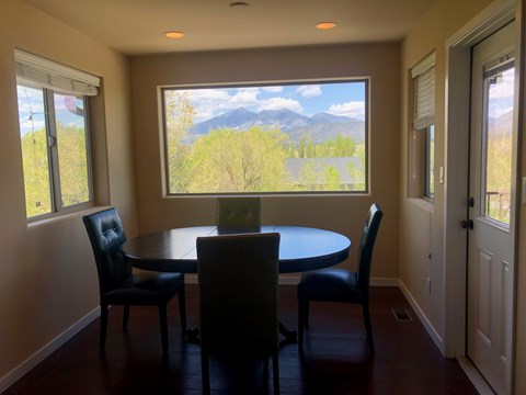 A dining room with a table and chairs and a view of the mountains outside.