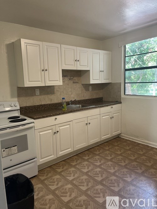 A kitchen with white cabinets and a tiled floor.