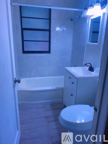 A white toilet sits in a bathroom next to a bathtub.