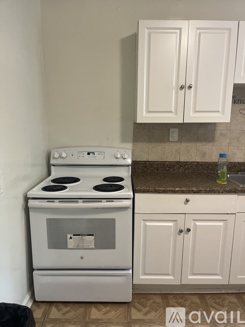 A white stove in a kitchen with white cabinets.
