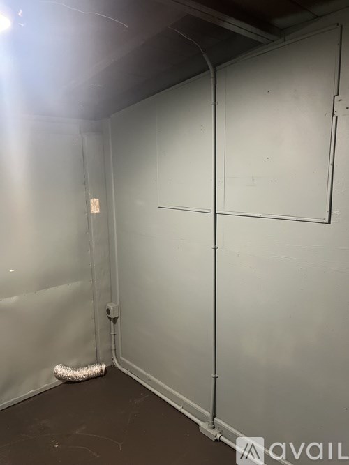 A room with a white wall and a white floor with a white object on the floor.