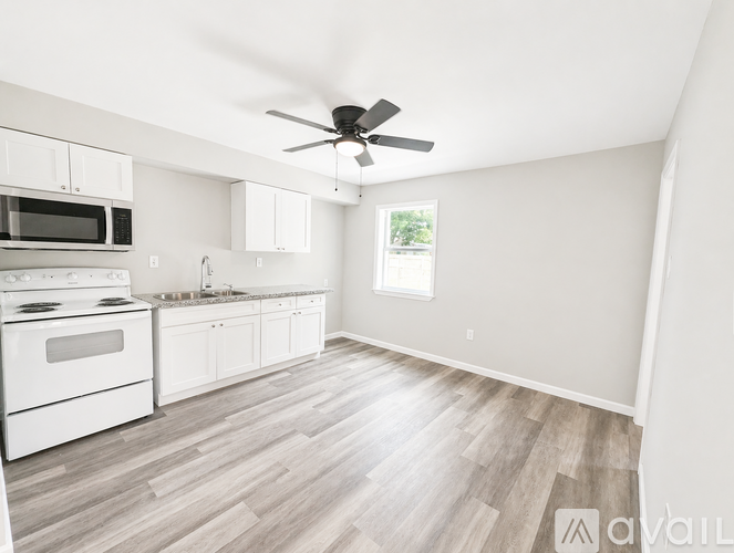A spacious kitchen with white appliances and wooden flooring.