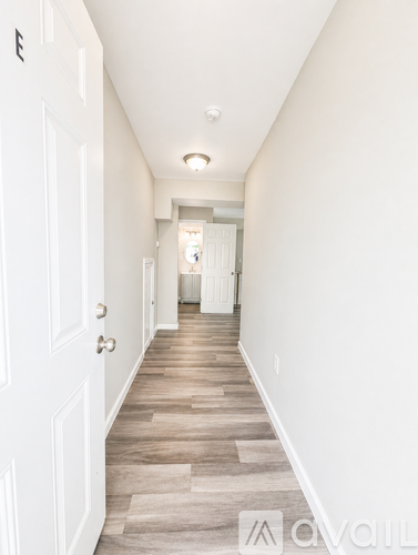 A long hallway with white doors and wood flooring.