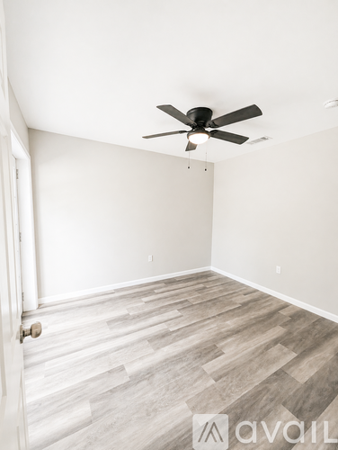 A room with a ceiling fan and wooden flooring.