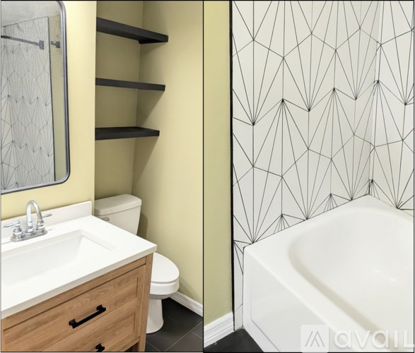 A bathroom with a white tub, sink, and a wallpapered wall.