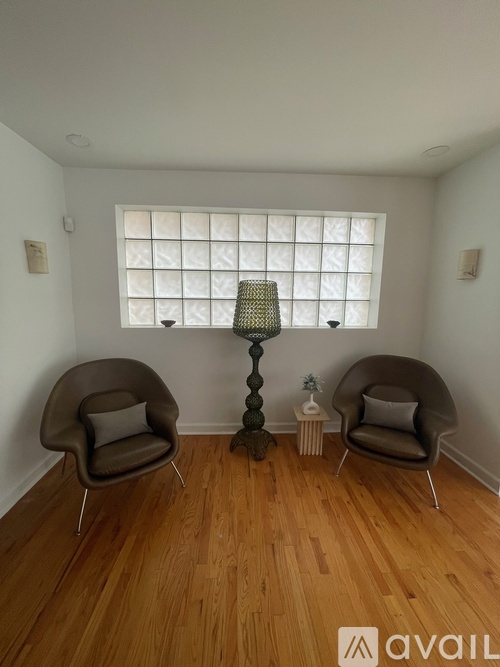 A room with two chairs and a table with a lamp on it.
