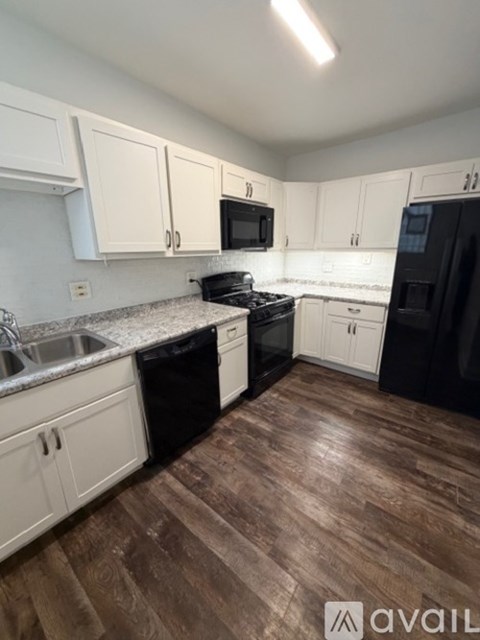 A kitchen with black appliances and white cabinets.