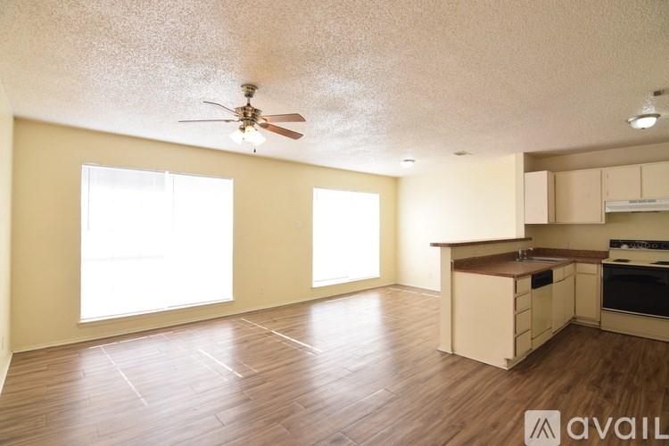 A spacious kitchen and living room with wooden flooring and a ceiling fan.