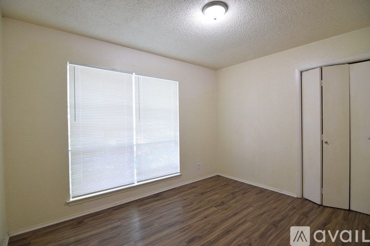 A room with a window covered in blinds and a wooden floor.