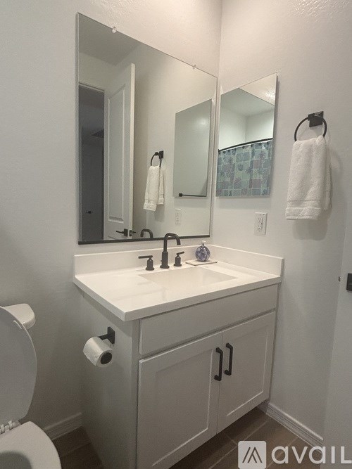 A white bathroom with a toilet, sink, and mirror.