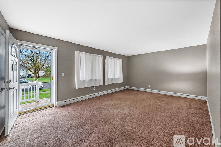 A room with a carpeted floor and a sliding glass door leading to a balcony.