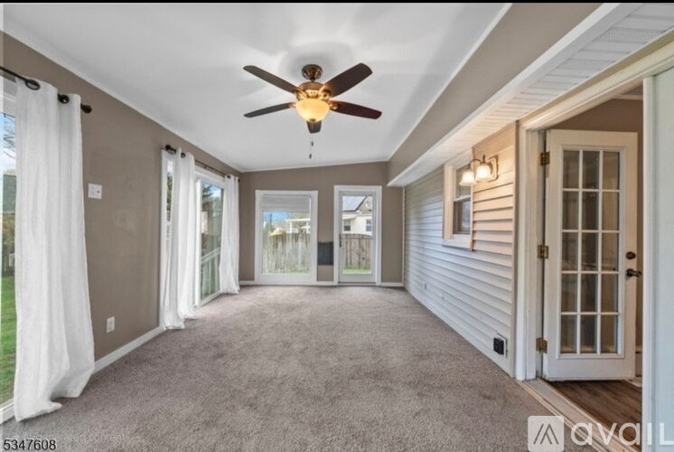 A spacious room with a ceiling fan and sliding glass doors.