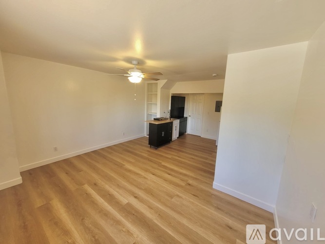 A room with a ceiling fan and wooden flooring.