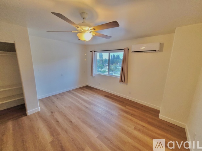 A kitchen with a white fridge, wooden floors, and a window.