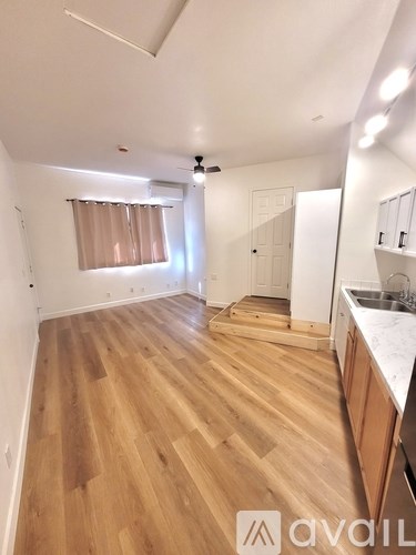 A kitchen with a white fridge, wooden floors, and a window.