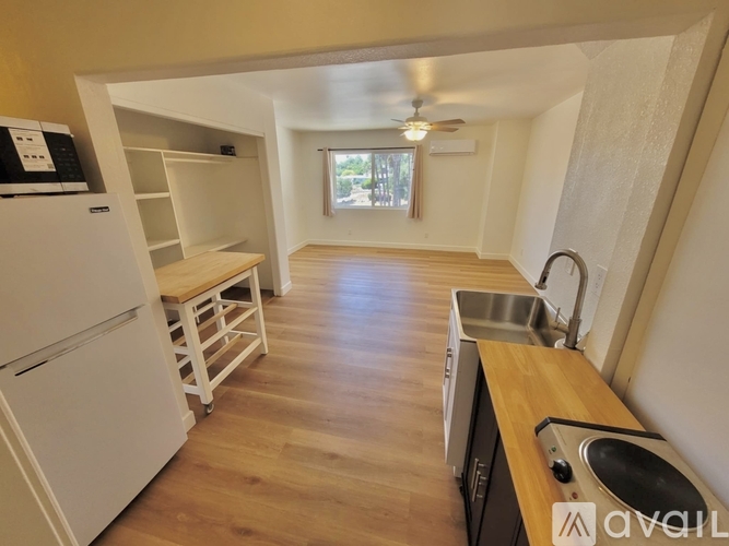 A kitchen with a white fridge and wooden floors.