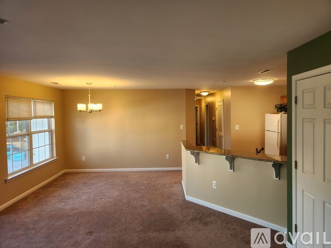 A spacious room with a carpeted floor and a large window.
