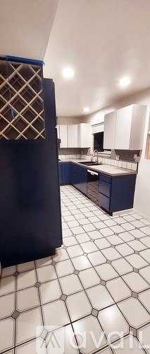 A kitchen with white tiled floors and blue cabinets.
