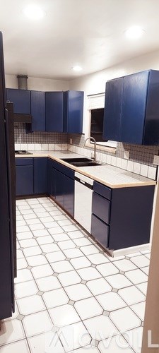 A kitchen with blue cabinets and white tiled floors.