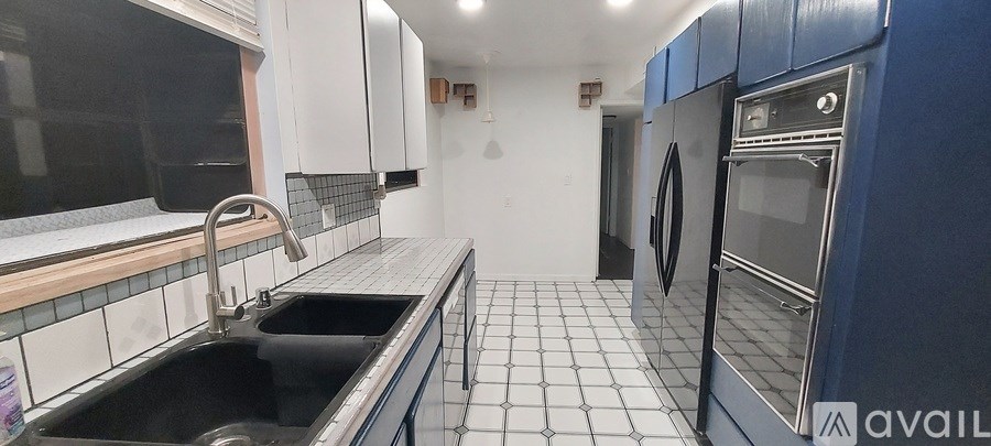 A kitchen with a black sink and blue cabinets.