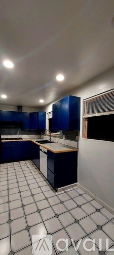 A kitchen with blue cabinets and white tiled flooring.