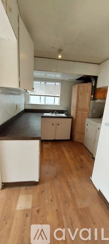 A kitchen with white cabinets and wooden floors.