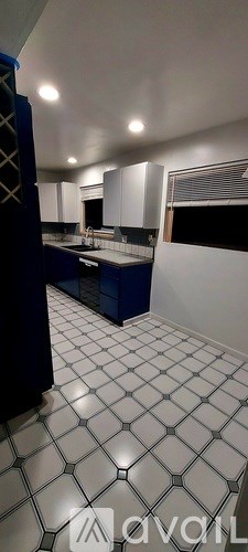 A kitchen with blue cabinets and white tiled flooring.