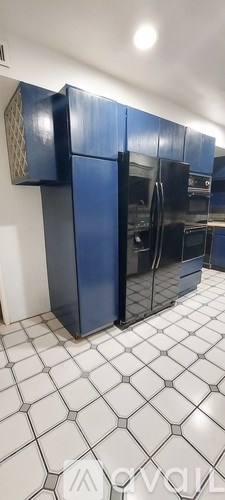 A kitchen with blue cabinets and a white tiled floor.