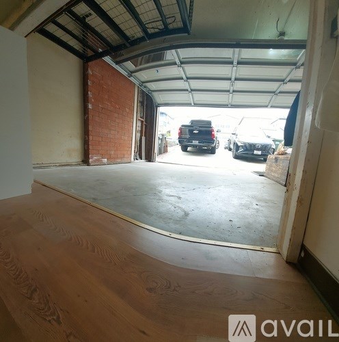 A garage with a wooden floor and a brick wall.
