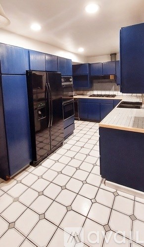 A kitchen with black appliances and blue cabinets.