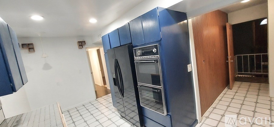 A kitchen with blue cabinets and a white tiled floor.