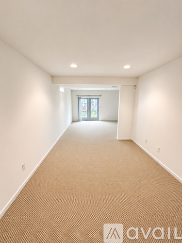 A long hallway with a carpeted floor and a door at the end.