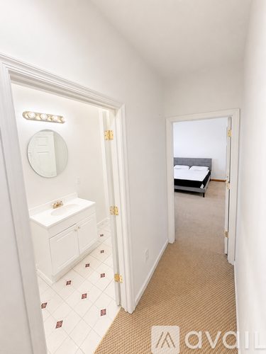 A kitchen area with a black refrigerator, white walls, and a carpeted floor.
