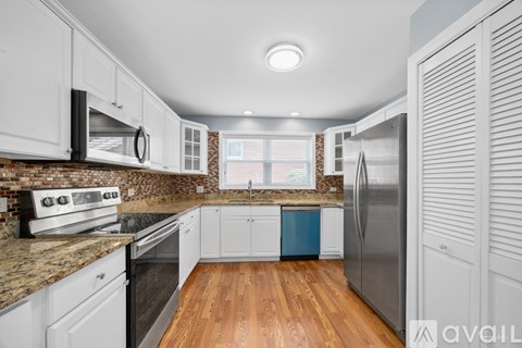 A kitchen with white cabinets and a brick backsplash.