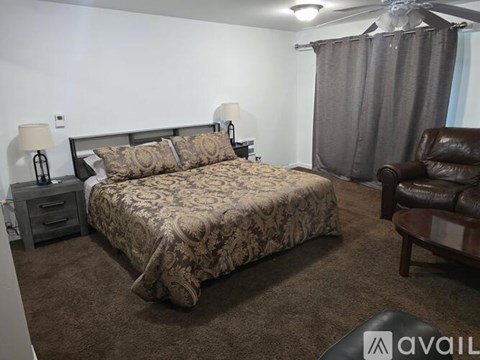A bedroom with a large bed and a brown leather chair.