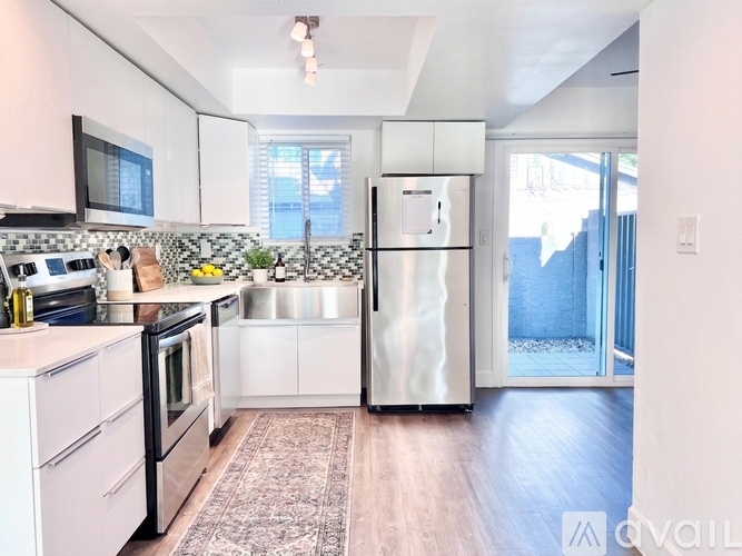 A kitchen with white cabinets and a refrigerator.